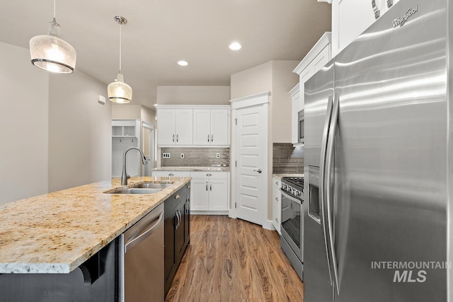 13991 W Milford Dr, Boise, ID 83713 - kitchen with appliances with stainless steel finishes, a sink, white cabinets, wood finished floors, and decorative light fixtures