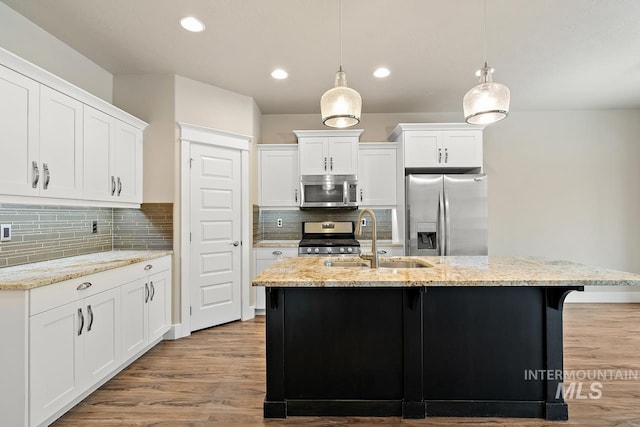 13991 W Milford Dr, Boise, ID 83713 - kitchen with stainless steel appliances, a sink, wood finished floors, decorative backsplash, and a kitchen island with sink