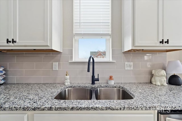 kitchen with sink, white cabinets, light stone counters, and decorative backsplash