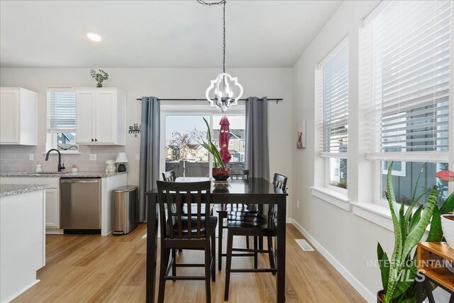 dining room featuring an inviting chandelier, sink, and light hardwood / wood-style floors