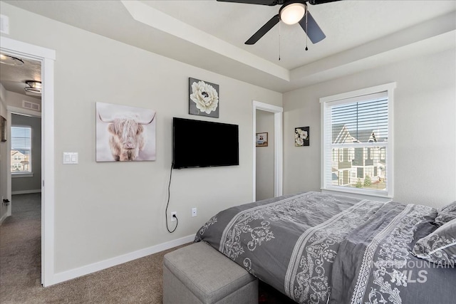 carpeted bedroom featuring ceiling fan and a raised ceiling