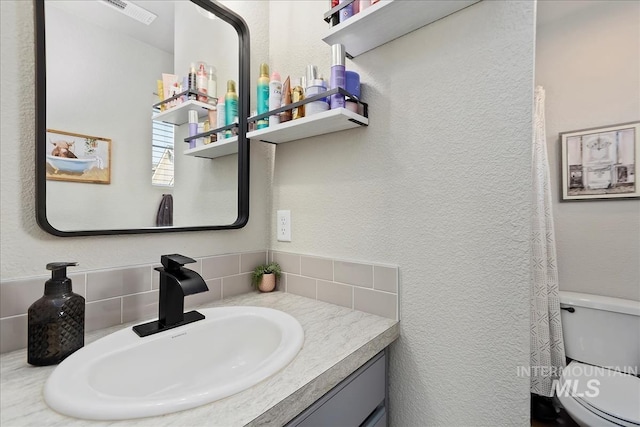 bathroom with tasteful backsplash, vanity, and toilet