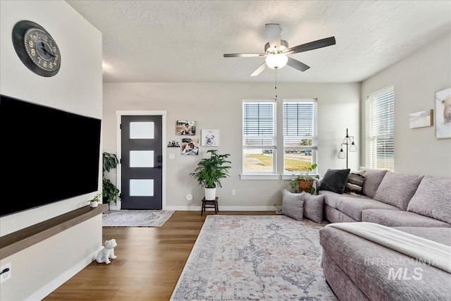 living room with dark wood-type flooring, ceiling fan, plenty of natural light, and a textured ceiling