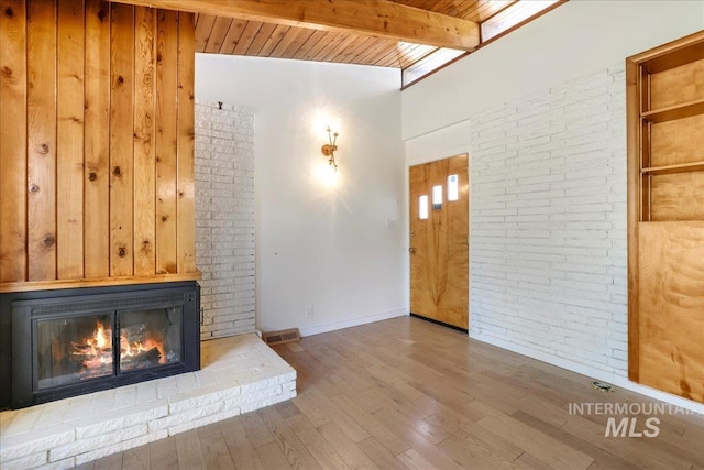 167 W Robbins, Twin Falls, ID 83301 - unfurnished living room with a glass covered fireplace, wood finished floors, a wooden ceiling with exposed beams, and brick wall