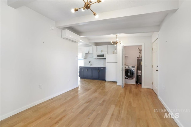 167 W Robbins, Twin Falls, ID 83301 - unfurnished living room with a chandelier, washer / dryer, a wall mounted AC, beamed ceiling, and light wood-style flooring