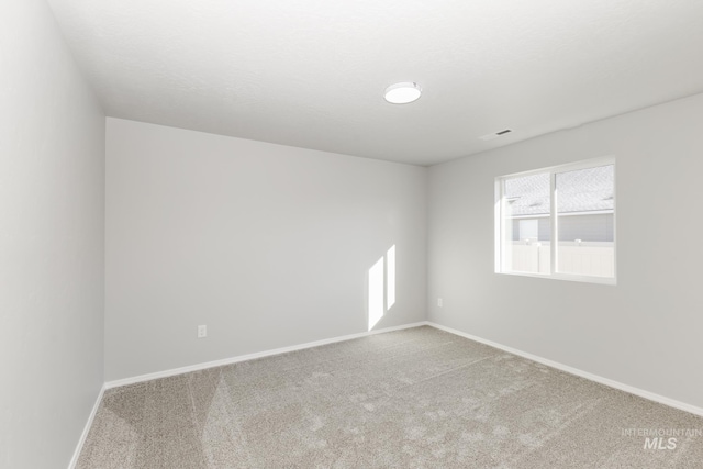 empty room with baseboards, carpet floors, and visible vents