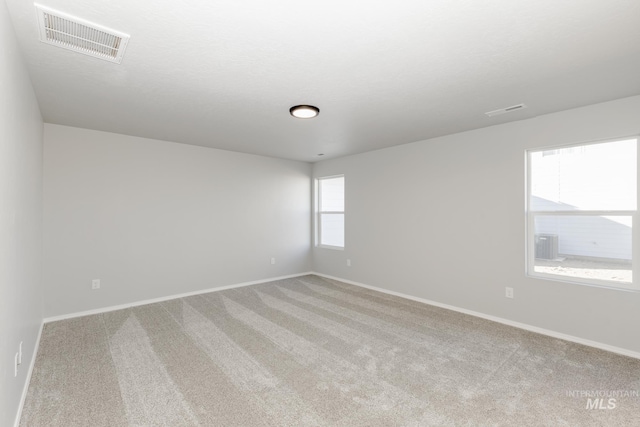 carpeted empty room featuring baseboards and visible vents