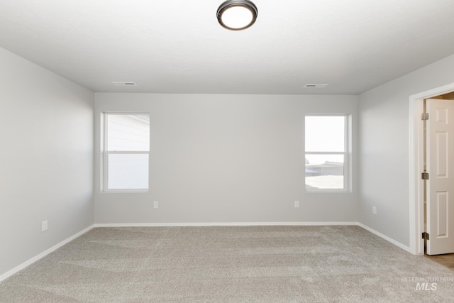 unfurnished room featuring light carpet, visible vents, and plenty of natural light