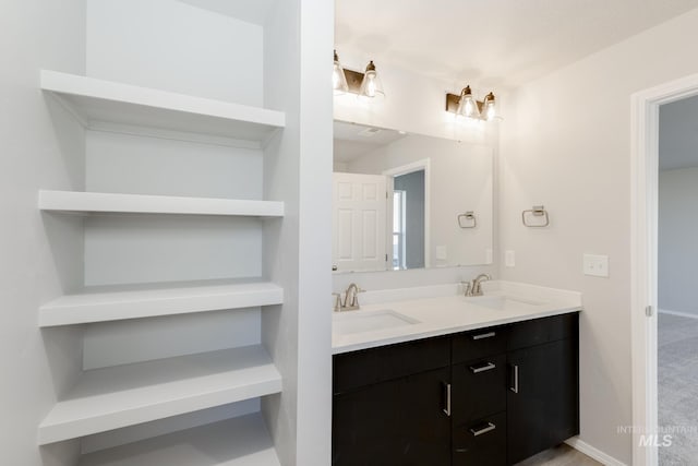 bathroom with a sink, baseboards, and double vanity