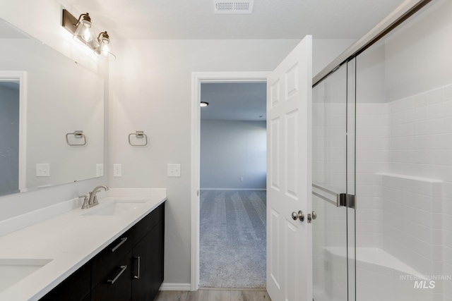 bathroom with double vanity, visible vents, a shower stall, and a sink