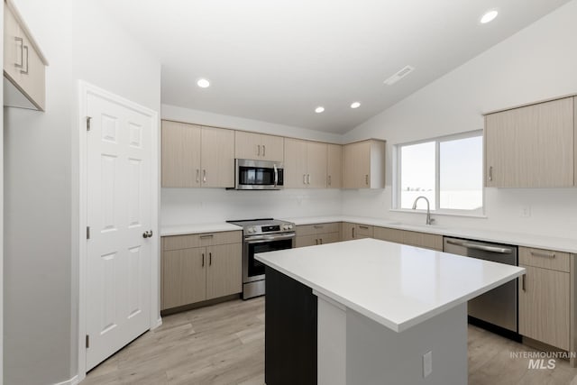 kitchen featuring lofted ceiling, a sink, light countertops, appliances with stainless steel finishes, and backsplash