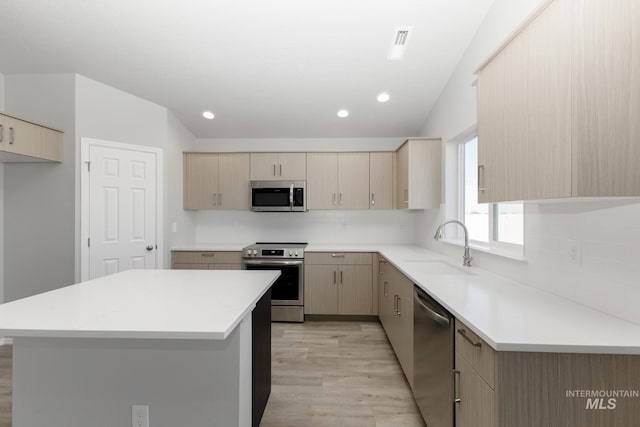 kitchen featuring a sink, tasteful backsplash, appliances with stainless steel finishes, and light brown cabinetry