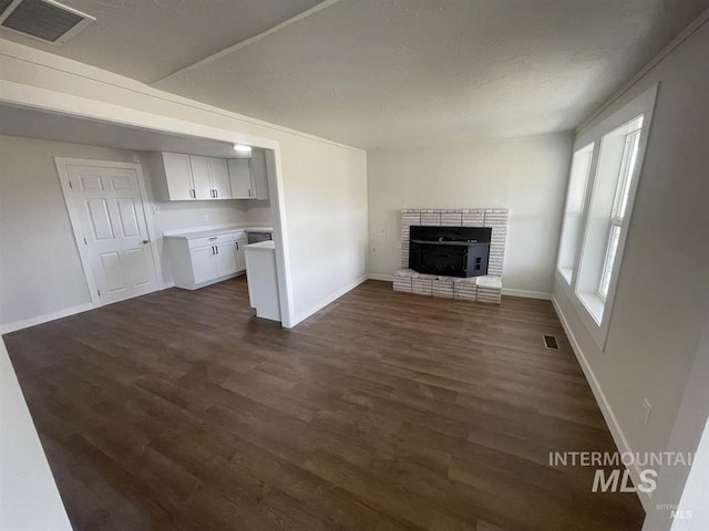 956 SE Hamilton Rd, Mountain Home, ID 83647 - unfurnished living room with dark wood finished floors, a brick fireplace, and baseboards
