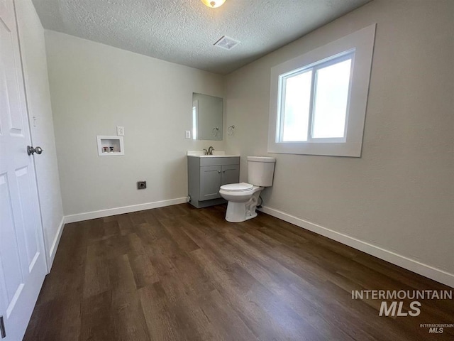 956 SE Hamilton Rd, Mountain Home, ID 83647 - bathroom featuring vanity, toilet, wood finished floors, a textured ceiling, and baseboards