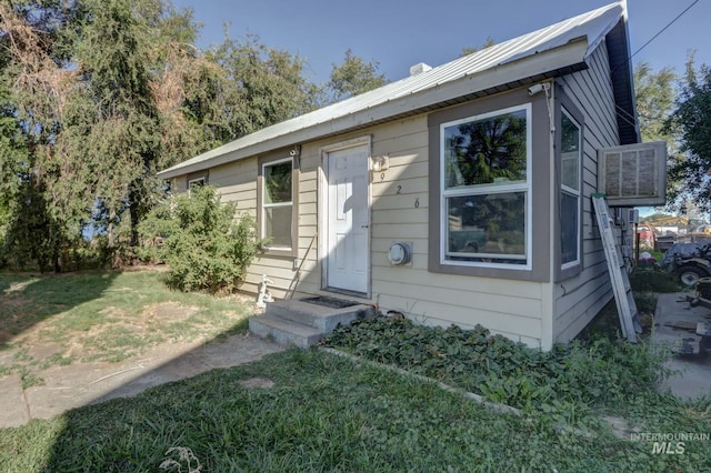 view of front of house with entry steps, metal roof, and a front yard