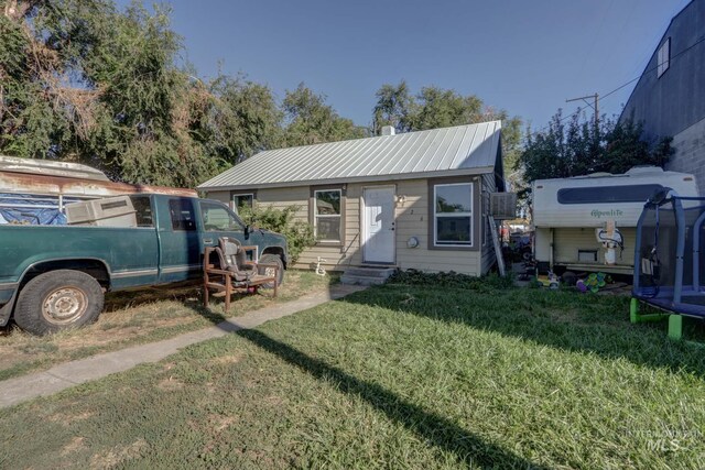 rear view of house featuring a trampoline and a yard