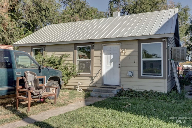 view of front of property featuring entry steps, metal roof, and a chimney