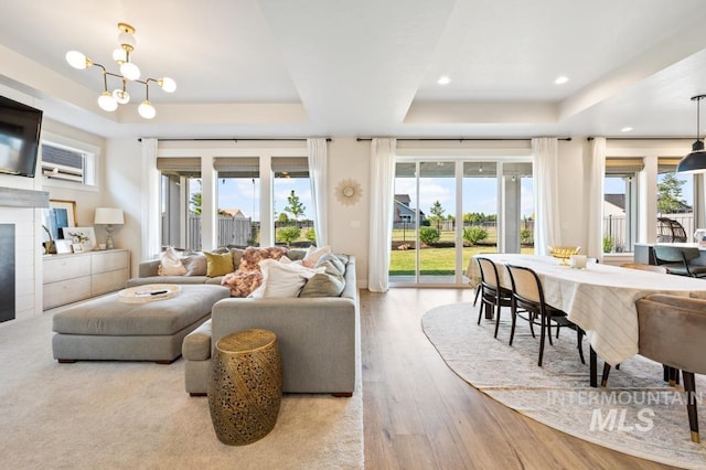 10411 Hazy Glen Dr, Nampa, ID 83687 - living room featuring a tray ceiling, hardwood / wood-style flooring, a tiled fireplace, a chandelier, and recessed lighting