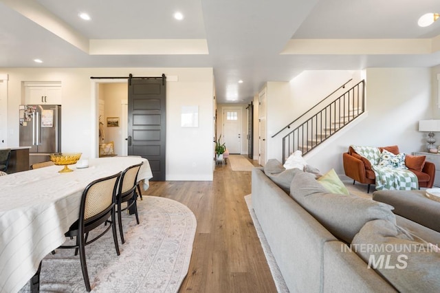 10411 Hazy Glen Dr, Nampa, ID 83687 - living area featuring a barn door, a raised ceiling, light wood finished floors, stairway, and recessed lighting