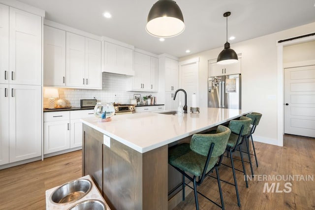 10411 Hazy Glen Dr, Nampa, ID 83687 - kitchen featuring appliances with stainless steel finishes, light wood-style flooring, a breakfast bar area, tasteful backsplash, and recessed lighting