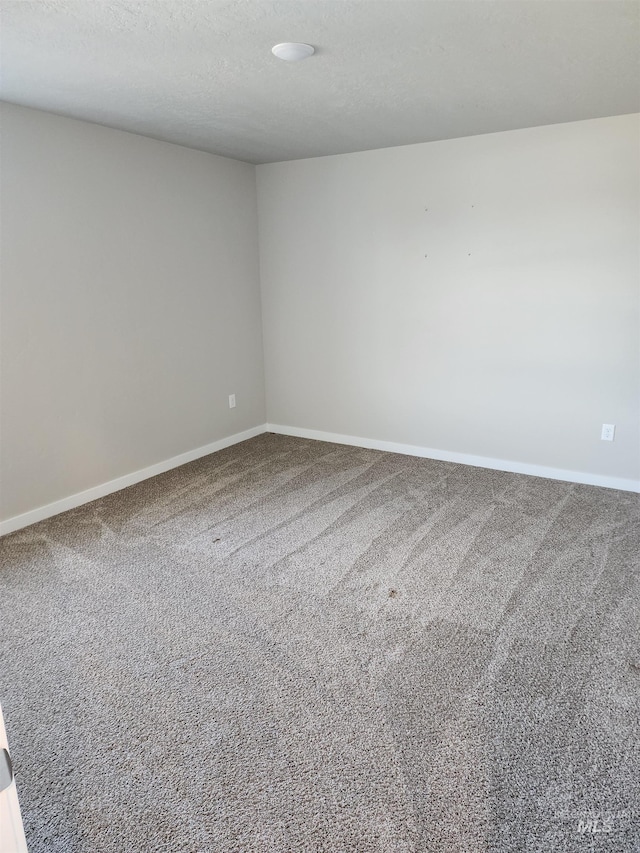 empty room with carpet floors and a textured ceiling