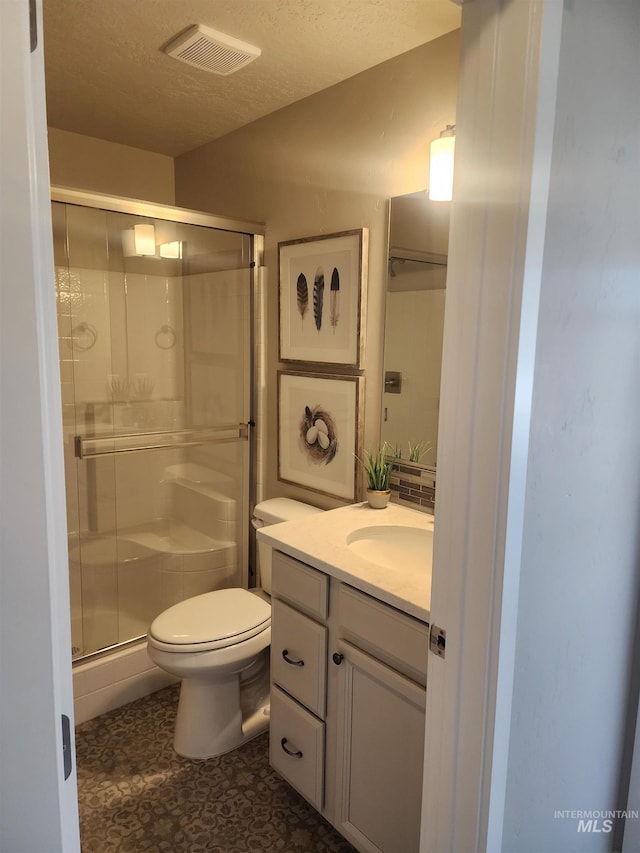 bathroom with walk in shower, vanity, toilet, and a textured ceiling