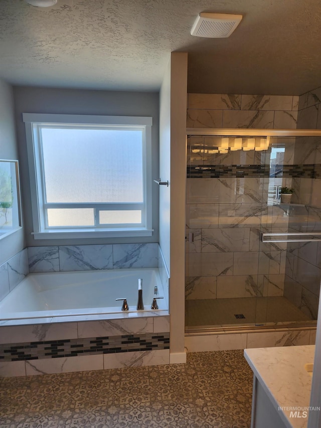 bathroom featuring vanity, plenty of natural light, a textured ceiling, and separate shower and tub