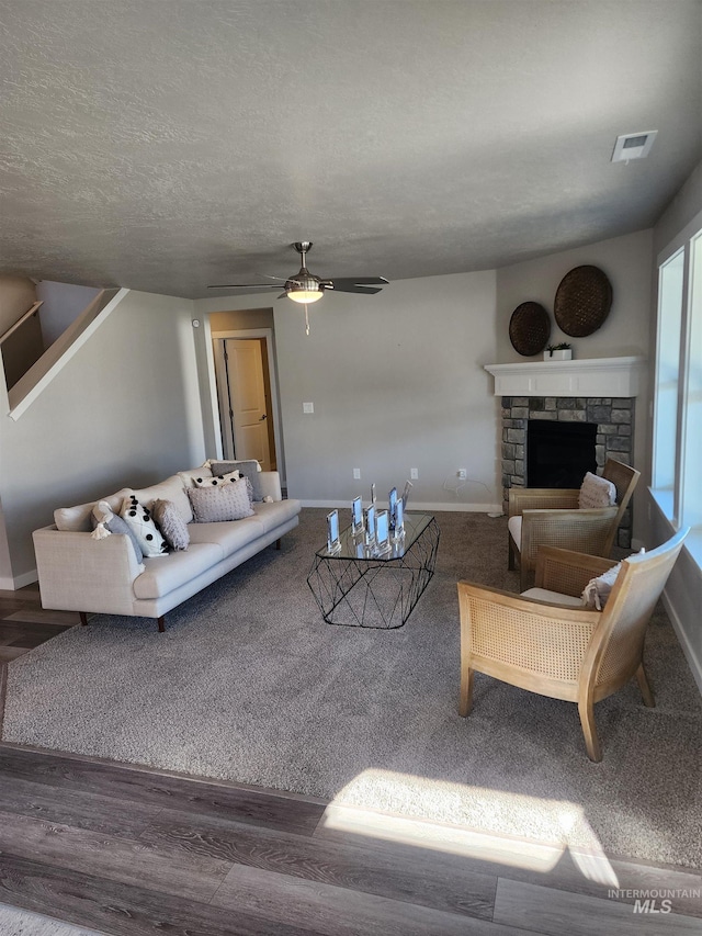 living room featuring ceiling fan, hardwood / wood-style floors, a textured ceiling, and a fireplace