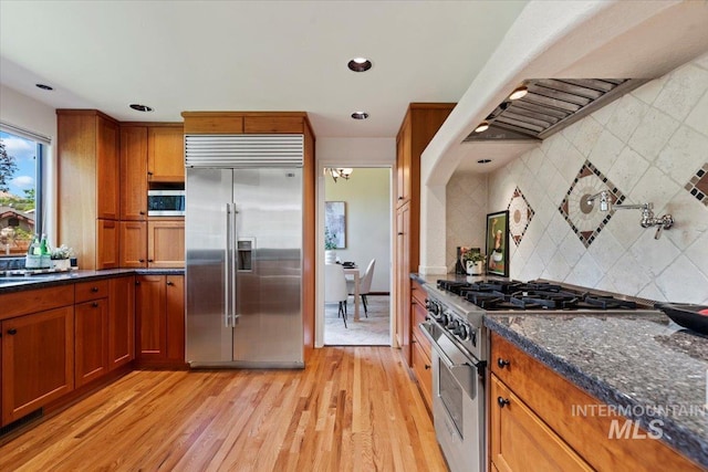 1814 E Spinnaker Ct, Boise, ID 83706 - kitchen featuring high quality appliances, tasteful backsplash, brown cabinets, dark stone countertops, and light wood-style flooring