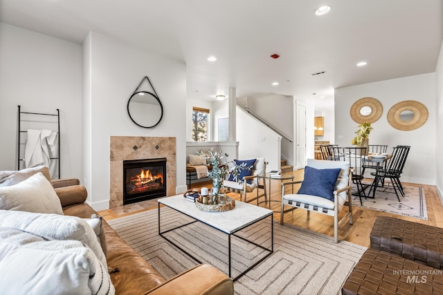 living area featuring stairs, a tiled fireplace, wood finished floors, and recessed lighting