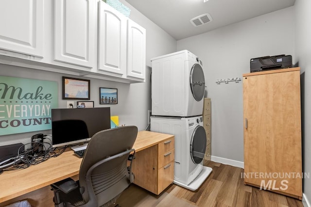 home office featuring stacked washer and dryer and hardwood / wood-style flooring