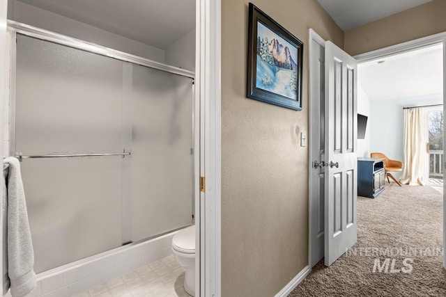 bathroom featuring a shower with shower door and toilet