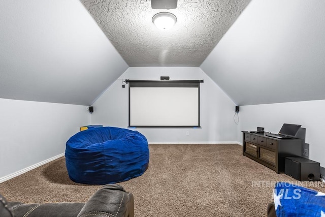 cinema room with carpet floors, a textured ceiling, and vaulted ceiling