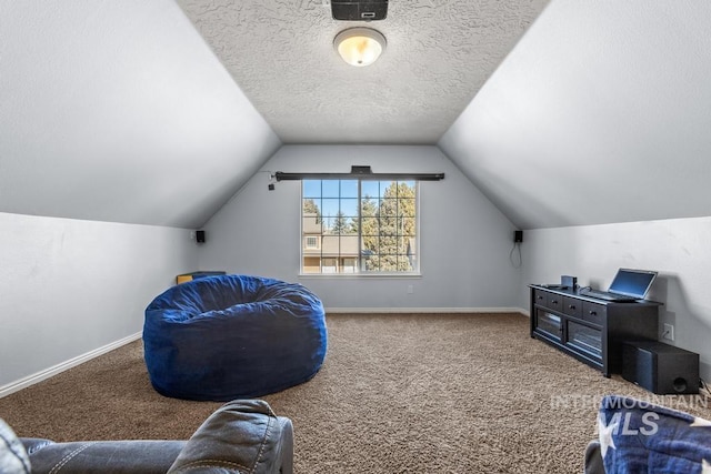 interior space featuring carpet flooring, vaulted ceiling, and a textured ceiling