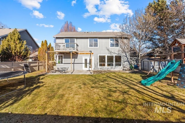 rear view of house featuring a playground, a patio, a balcony, a storage unit, and a trampoline