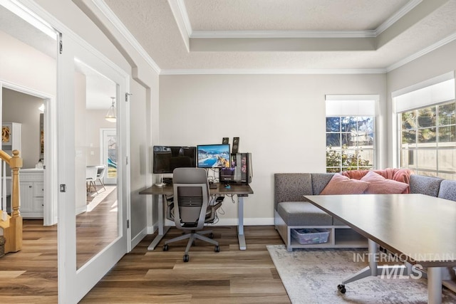 office area with hardwood / wood-style flooring, ornamental molding, a raised ceiling, and a textured ceiling