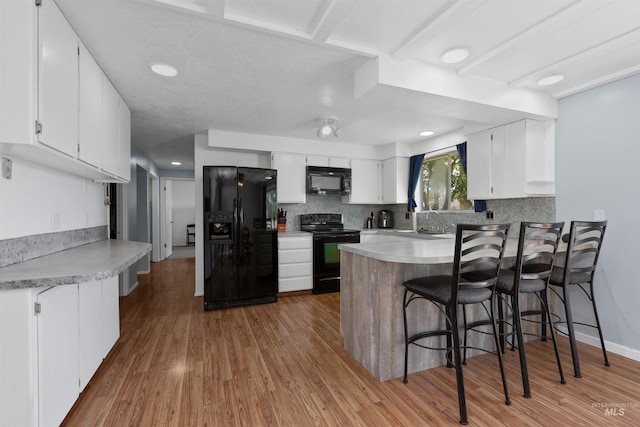 101 Patton St, Marsing, ID 83639 - kitchen with black appliances, a peninsula, light wood finished floors, backsplash, and recessed lighting