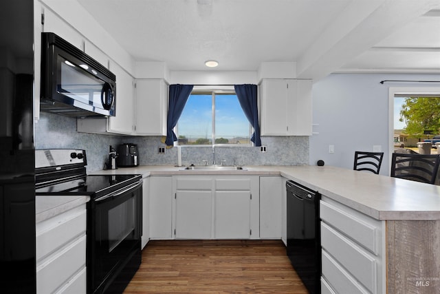 101 Patton St, Marsing, ID 83639 - kitchen with black appliances, a sink, a peninsula, decorative backsplash, and light countertops