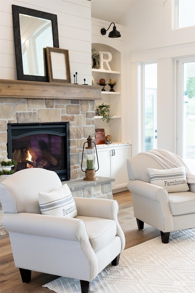 living area with a fireplace, built in shelves, and light wood-type flooring