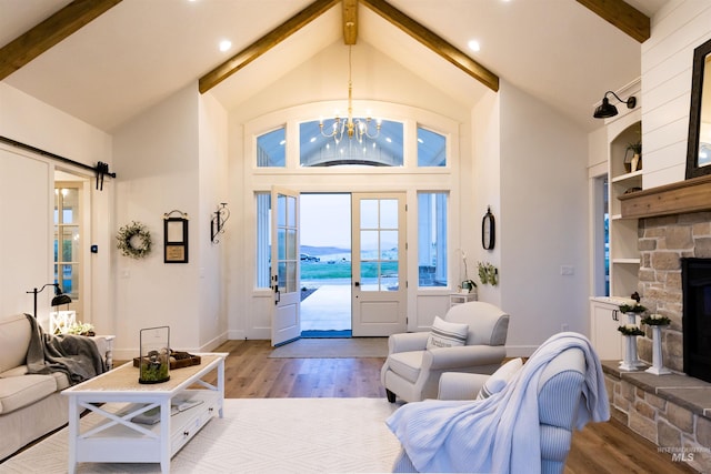 living room with a fireplace, light hardwood / wood-style flooring, lofted ceiling with beams, and an inviting chandelier