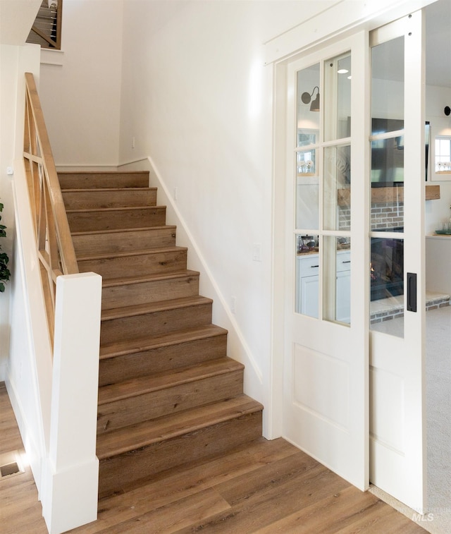 stairs with a fireplace and hardwood / wood-style floors