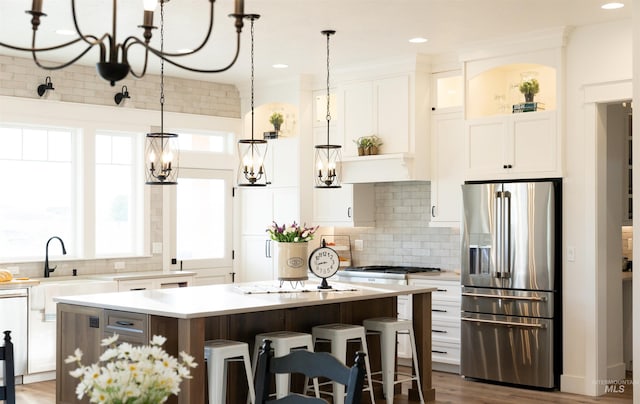 kitchen featuring tasteful backsplash, a breakfast bar, white cabinets, stainless steel fridge with ice dispenser, and a center island