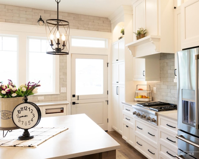 kitchen featuring backsplash, white cabinetry, hanging light fixtures, and stainless steel appliances