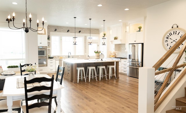 kitchen with a center island, white cabinets, a breakfast bar area, light hardwood / wood-style floors, and stainless steel appliances