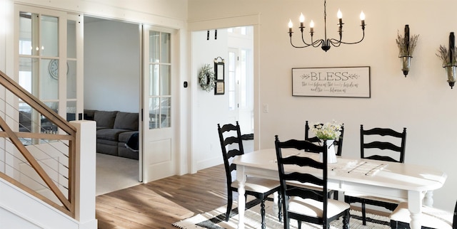 dining space featuring wood-type flooring and an inviting chandelier