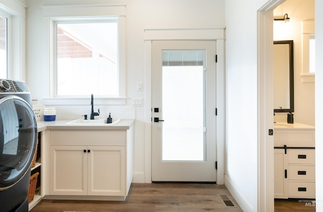 clothes washing area featuring cabinets, light wood-type flooring, sink, and washer / clothes dryer