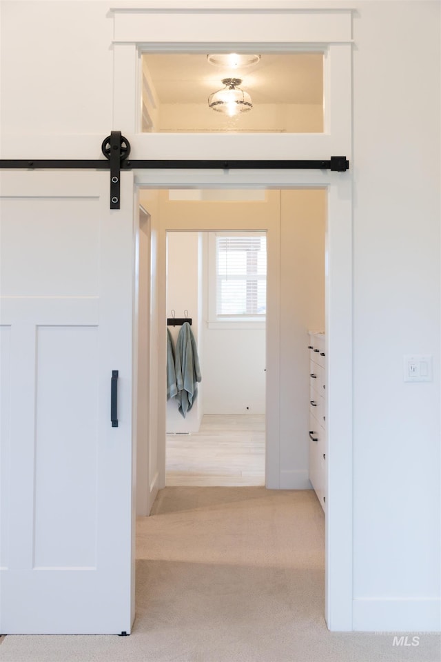 hallway with light carpet and a barn door