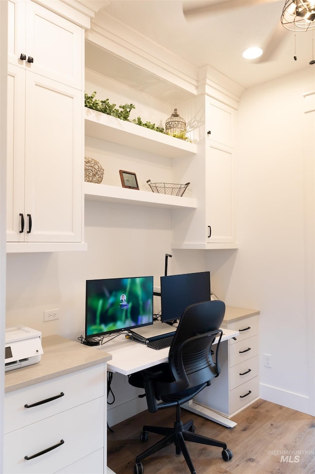 home office featuring light hardwood / wood-style floors and built in desk