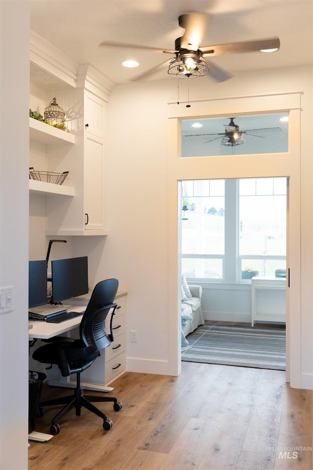 home office with light hardwood / wood-style flooring and ceiling fan