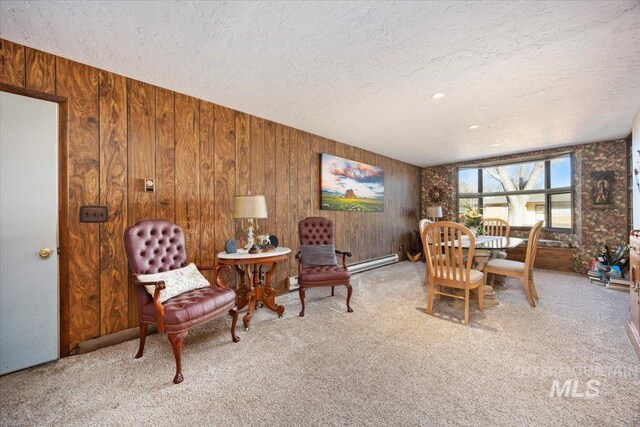carpeted dining space with a baseboard heating unit, a textured ceiling, and wood walls